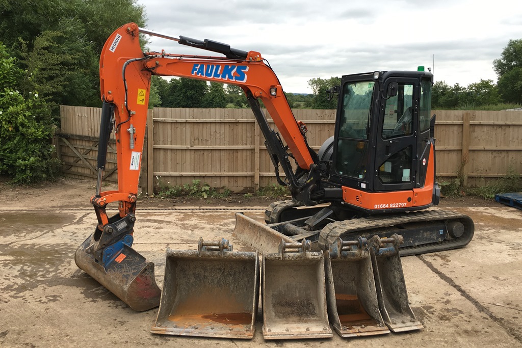 AE Faulks Excavator on car park with digger options lined up in front of machine