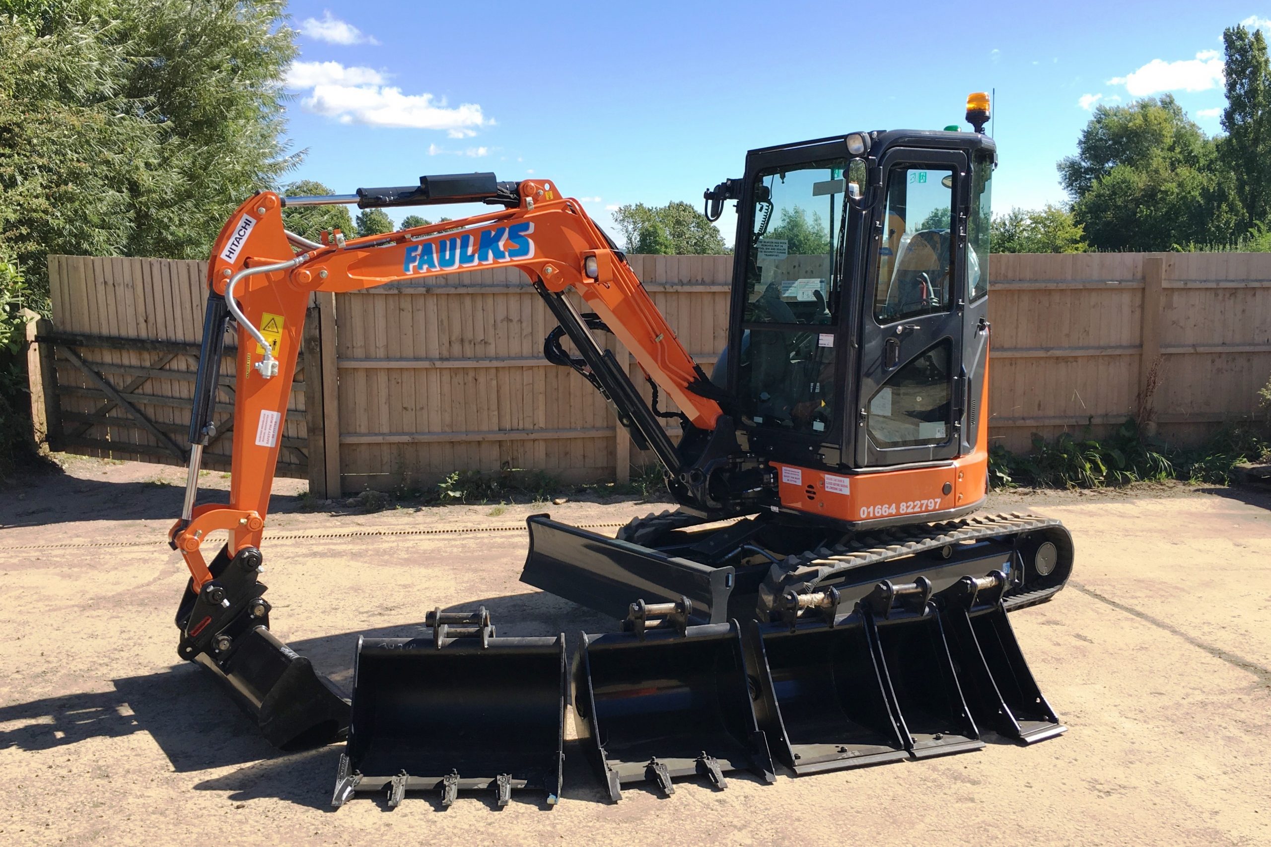 The Hitachi ZX33 tracked excavator in car park with digger head options lined up, side view