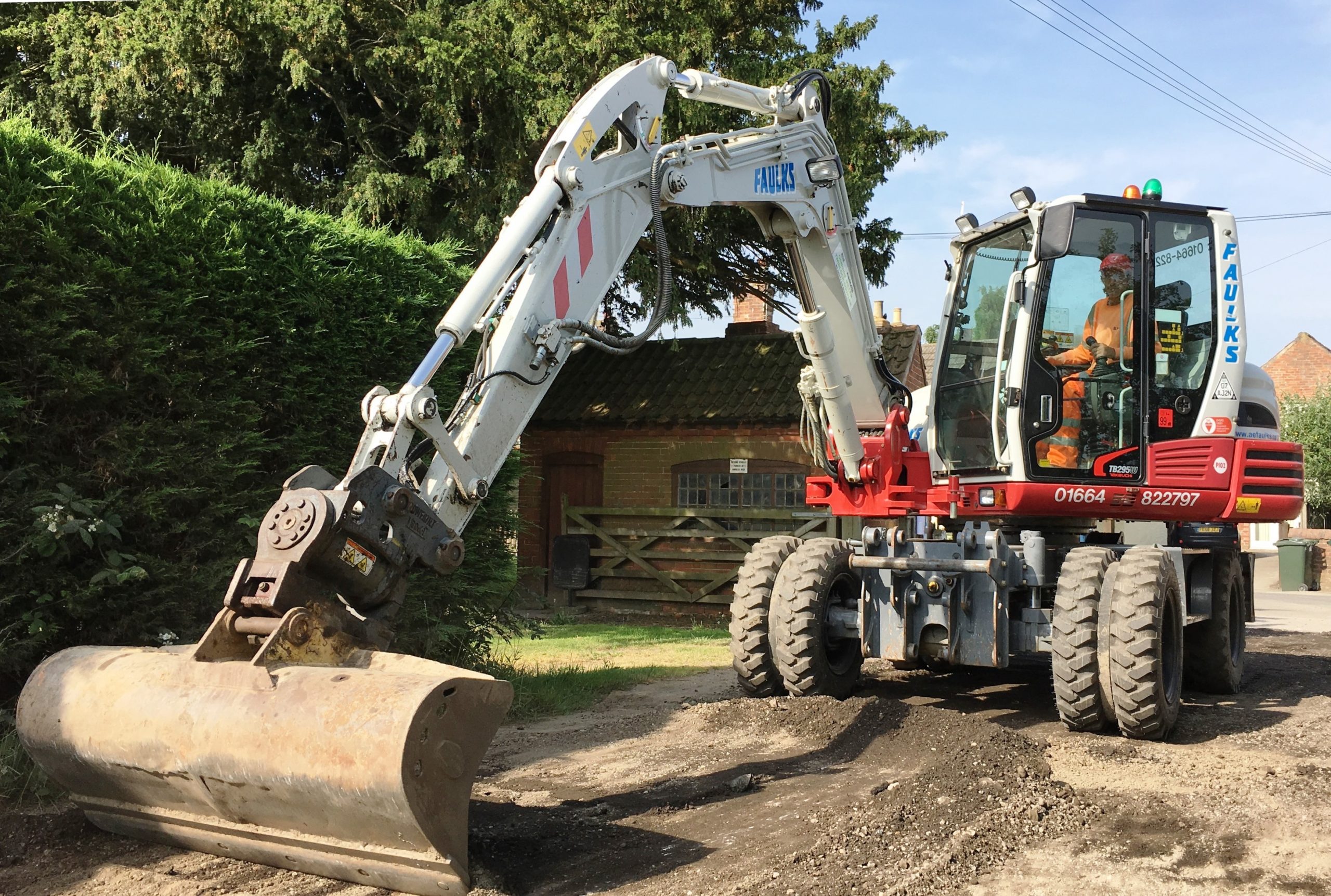 Takeuchi wheeled excavator for hire in use on driveaway